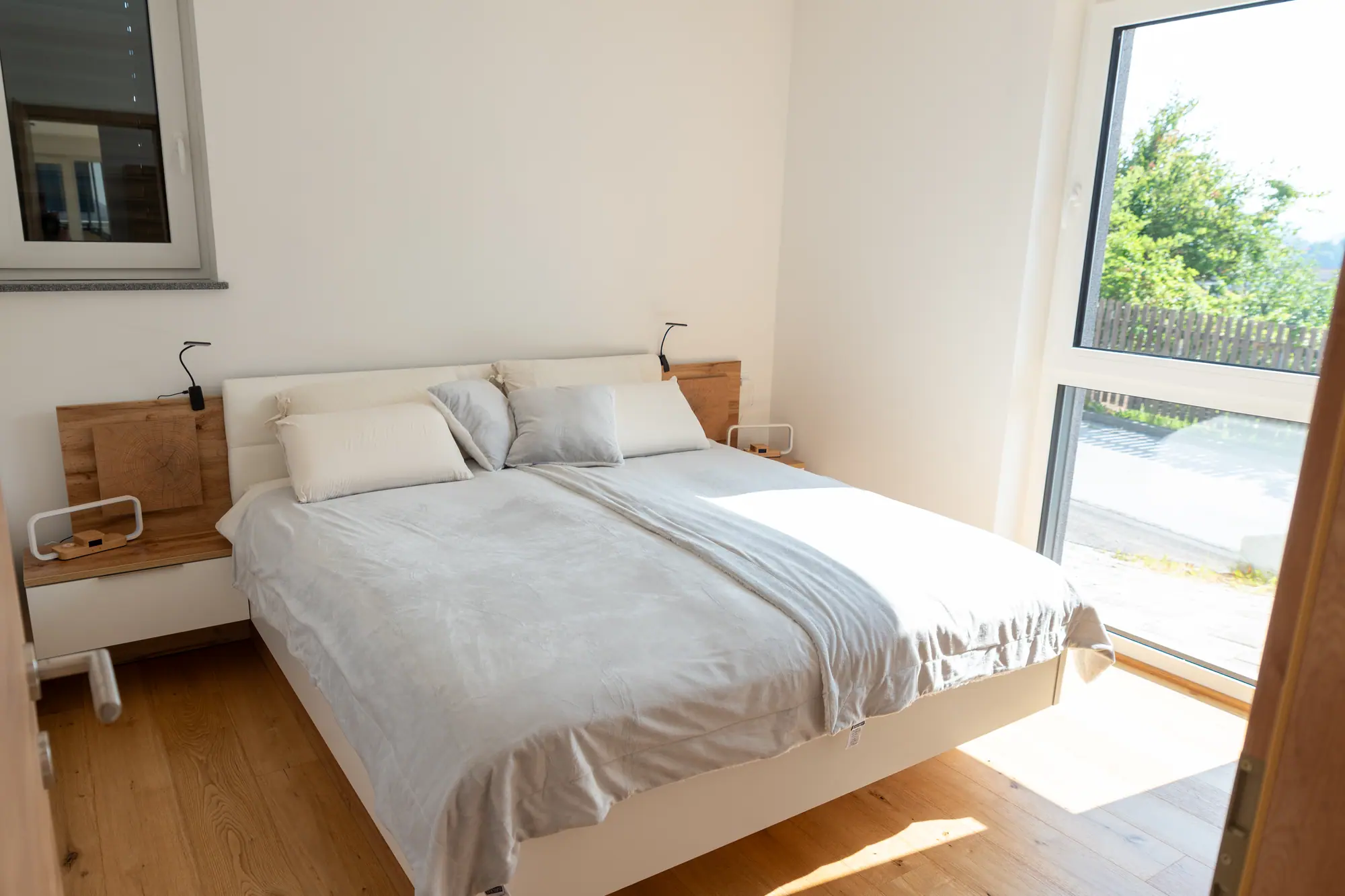 The main bedroom — a floating oak-and-white bed beneath a corner window