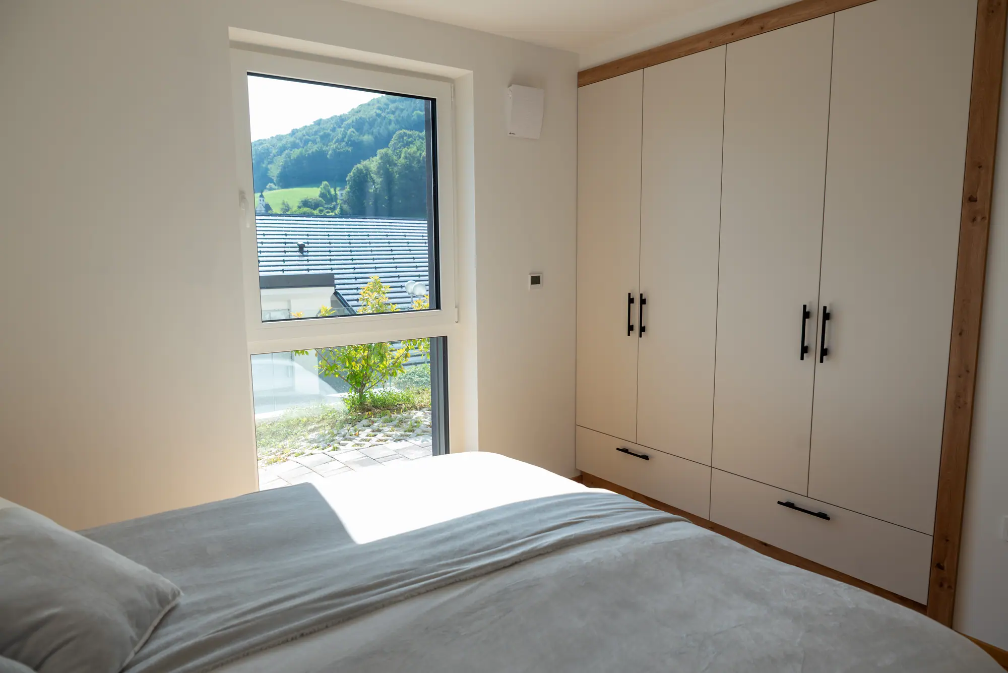 The main bedroom's oak-trimmed wardrobe beside a window onto the green hillside