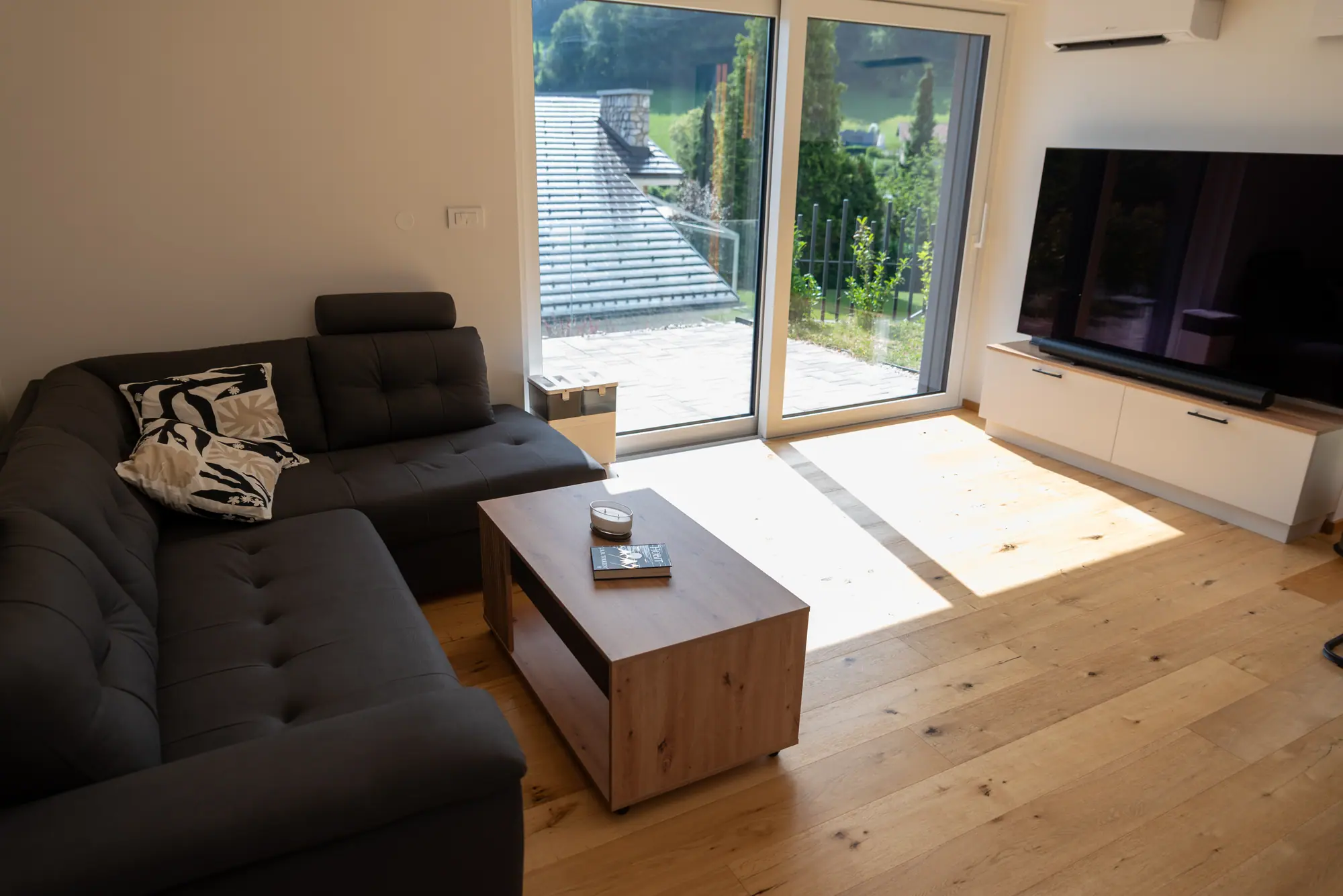 The sofa and oak table facing sliding glass doors over the valley